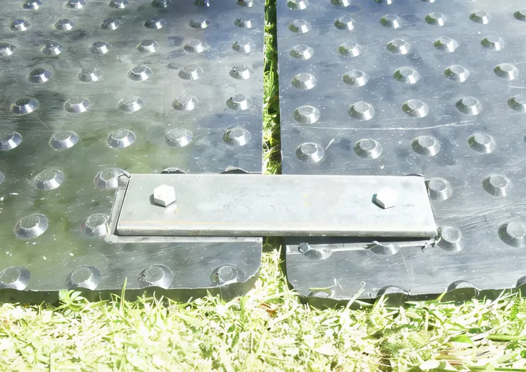 A steel lock joiner bolted across two black mats