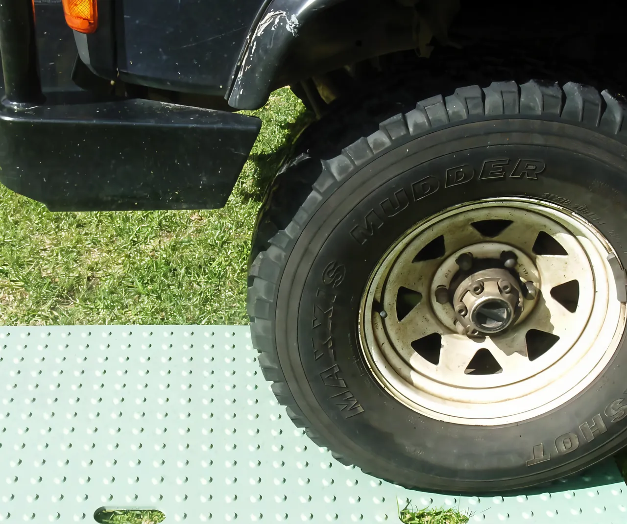 A four wheel drive tyre resting on a green PolyTrac ground protection mat